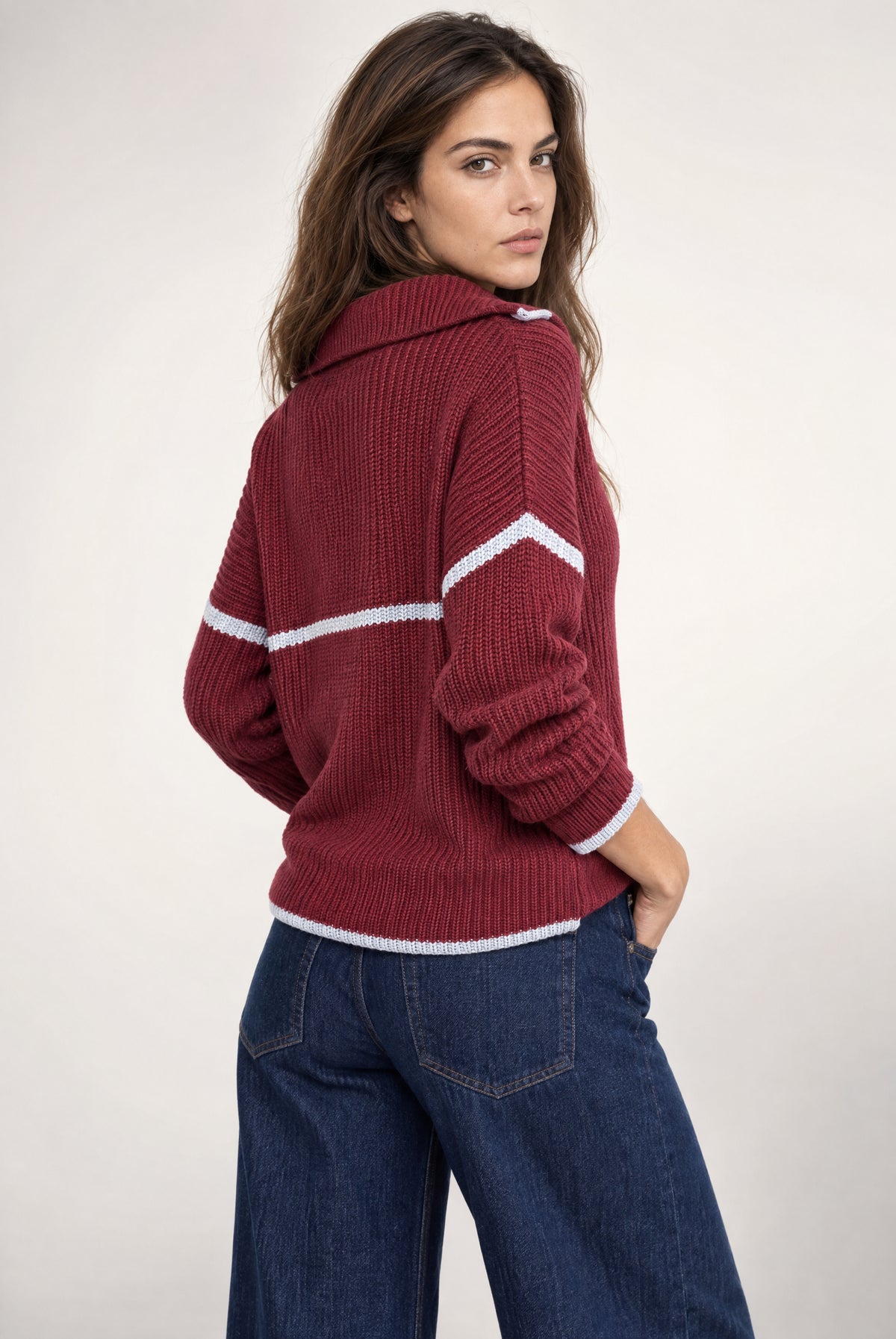 Burgundy ribbed half-zip sweater with white contrast trim stripes worn with dark denim jeans.