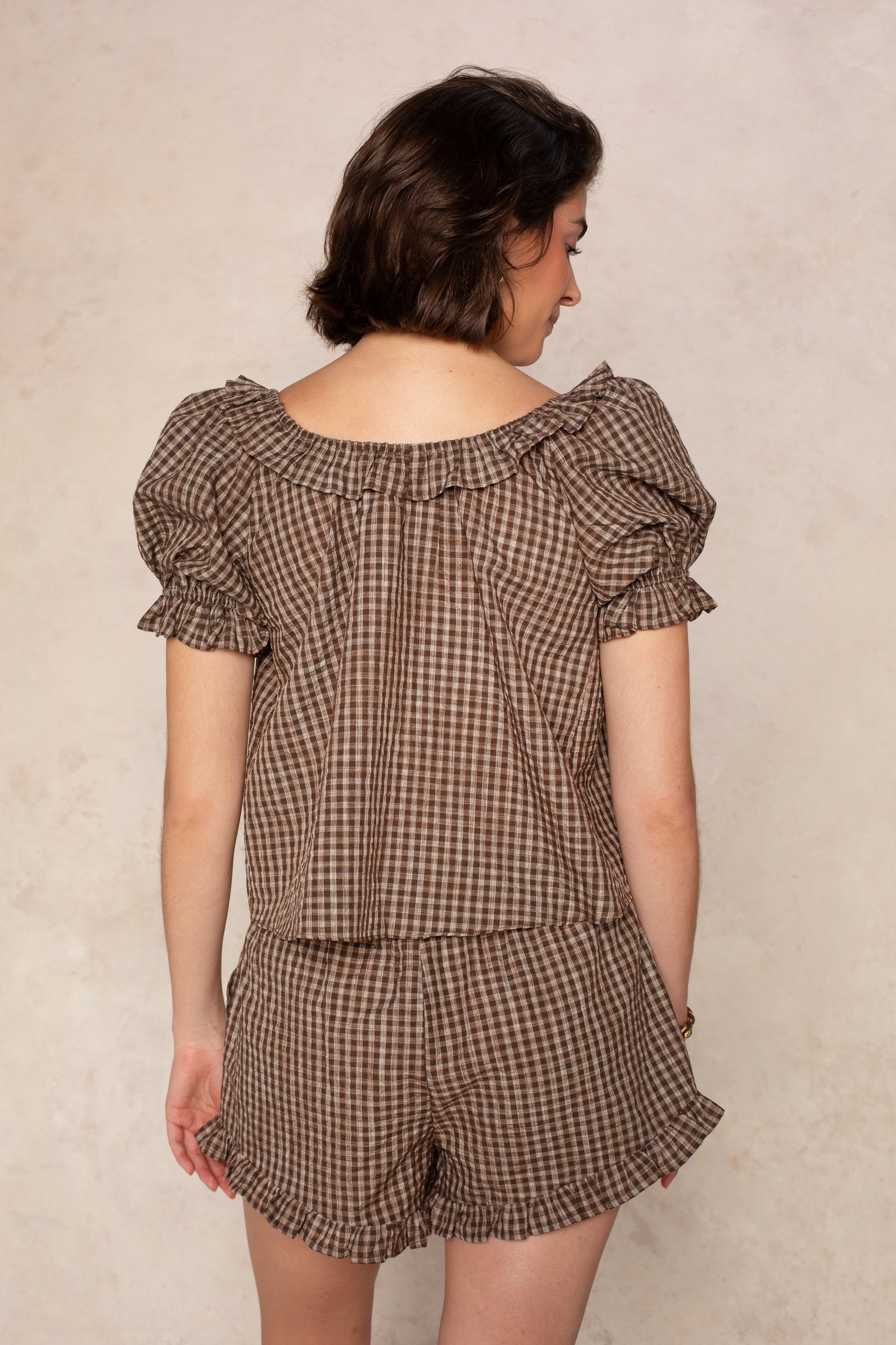 A person with short brown hair stands with their back to the camera, wearing the Isla Ellie Plaid Gingham Set Short against a neutral background.