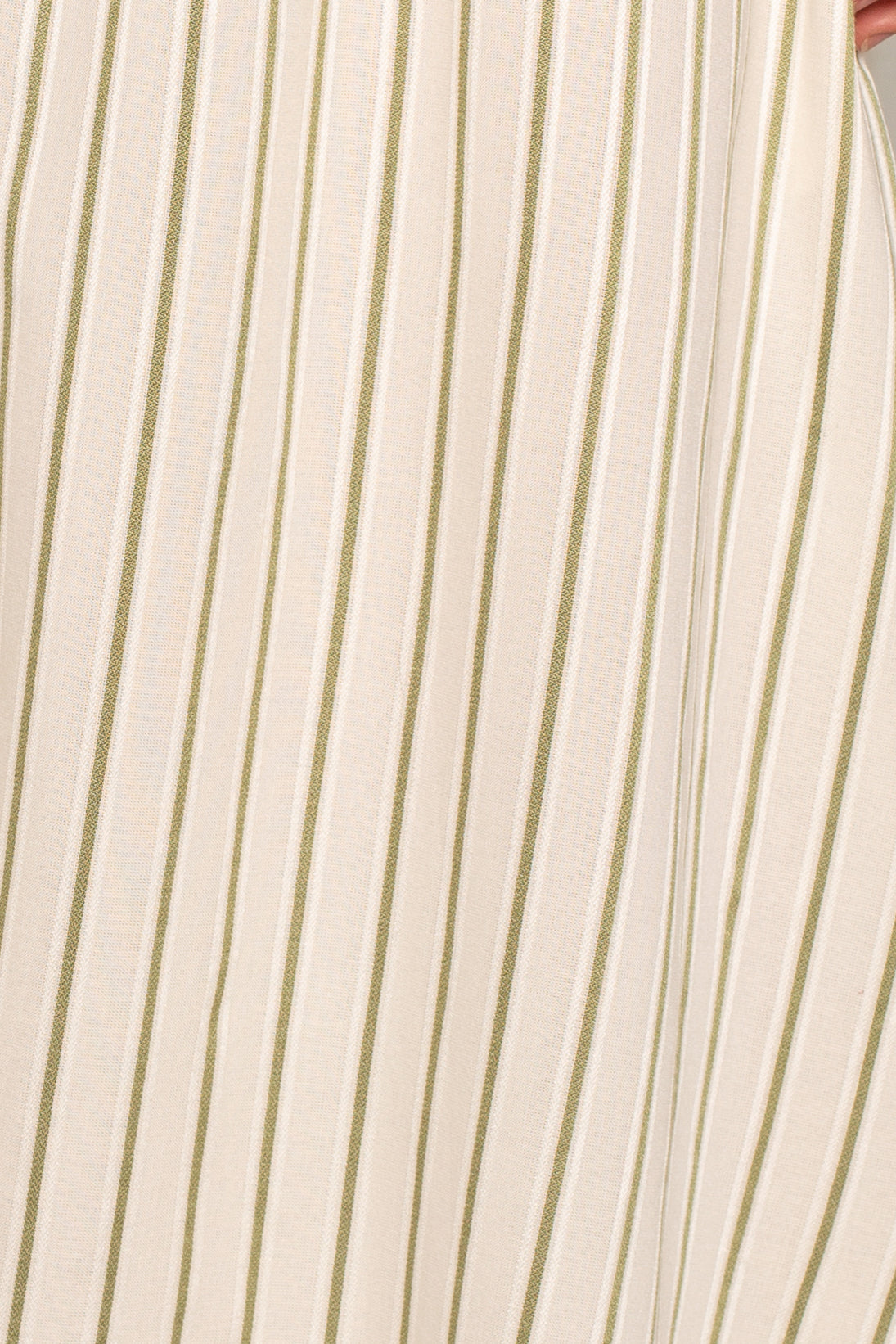 Close-up of the Grace Stripe Midi Skirt by Isla x Tate, featuring beige fabric with thin vertical green and white stripes, a smooth texture, and soft drape—ideal for an A-line silhouette or midi length with an elastic waist.