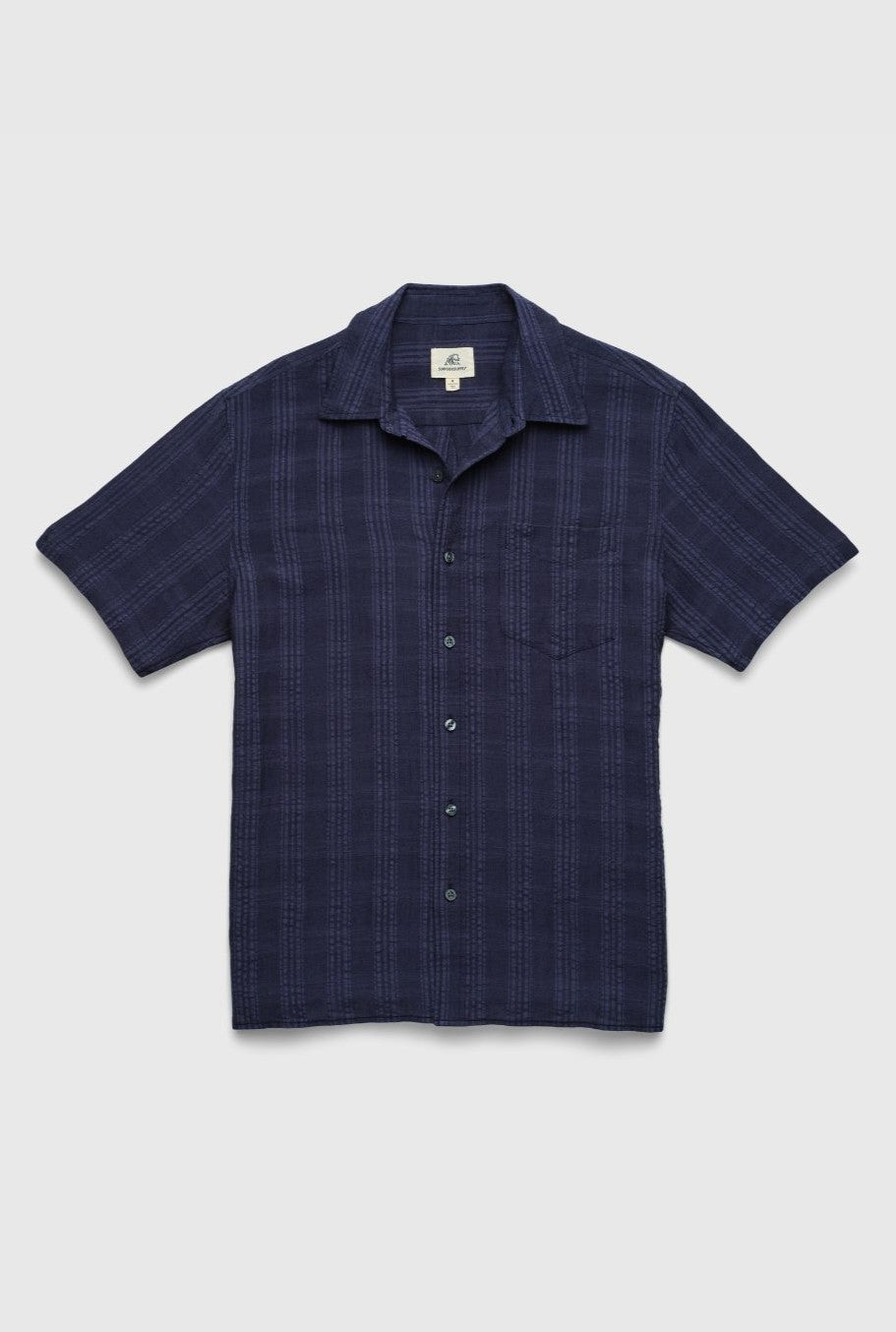 The Surfside Supply Co. Joseph Straight Bottom Textured Shirt is a navy blue, regular fit short-sleeve button-up with a subtle plaid pattern, single chest pocket, and soft cotton rayon fabric, shown laid flat on a white background.