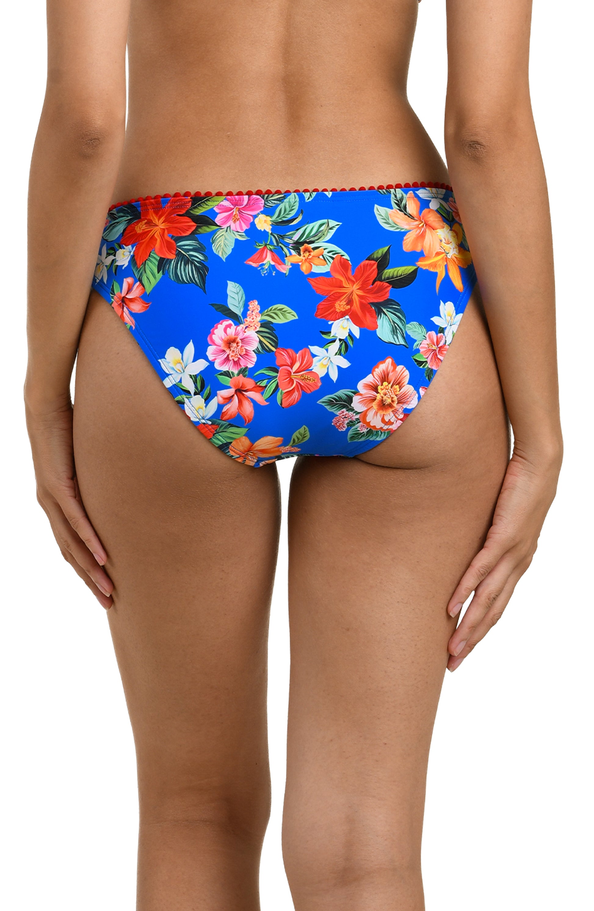 A woman is seen from the back wearing the La Blanca Modern Oasis Solid Hipster, featuring bright blue color and moderate rear coverage. Her arms are relaxed at her sides.