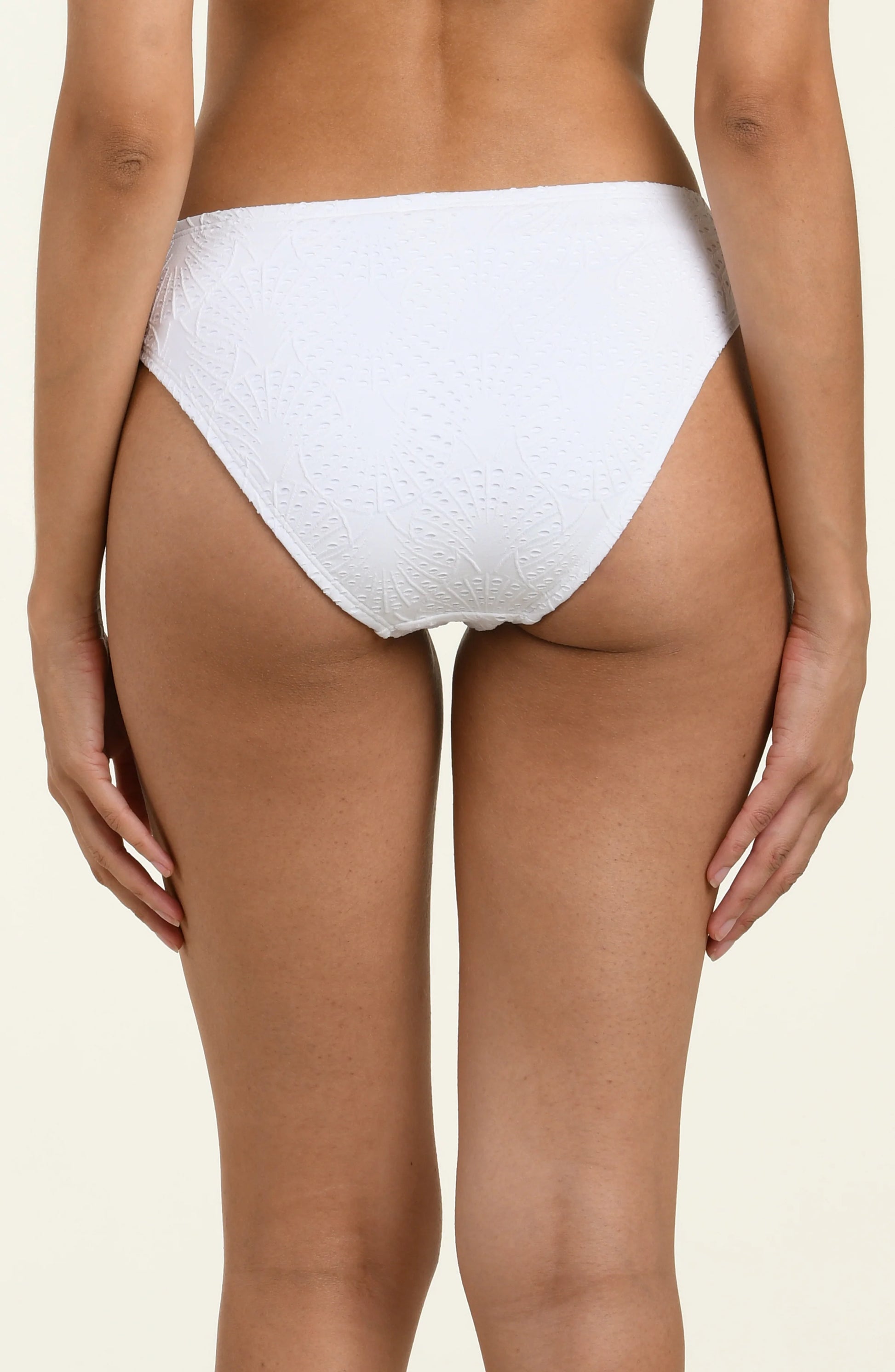 A person is shown from the back wearing the La Blanca White Shellbound Adjustable Loop Hipster bikini bottoms, featuring adjustable side ties, against a plain light background.