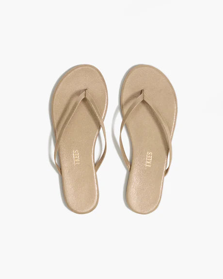 A pair of gold Glitters Tkees In Pink Pearl flip-flop sandals by Tkees, featuring a minimalist design with thin straps and a leather upper, viewed from above on a plain white background.