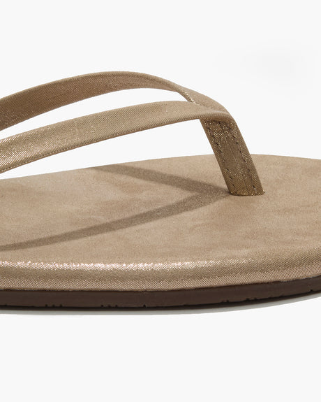 Close-up of the Glitters Tkees In Pink Pearl by Tkees, featuring metallic pink pearl straps, a leather upper, and a flat cushioned sole, shown against a white background.
