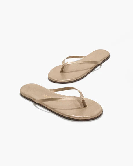 The Glitters Tkees in Pink Pearl by Tkees are stylish flip-flop sandals featuring a leather upper, thin straps, flat soles, and a durable rubber outsole, showcased on a plain white background.