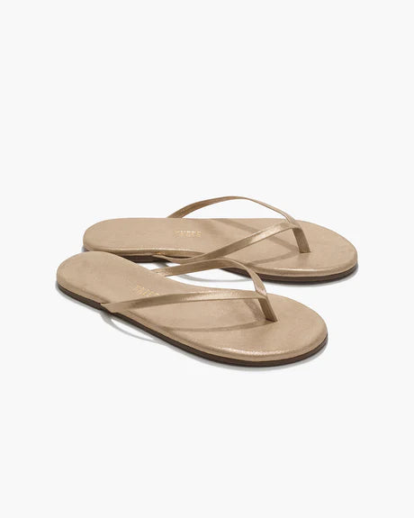 A pair of Glitters Tkees In Pink Pearl by Tkees featuring flat, open-toe flip-flop sandals with thin straps and a durable rubber outsole, displayed on a white background.