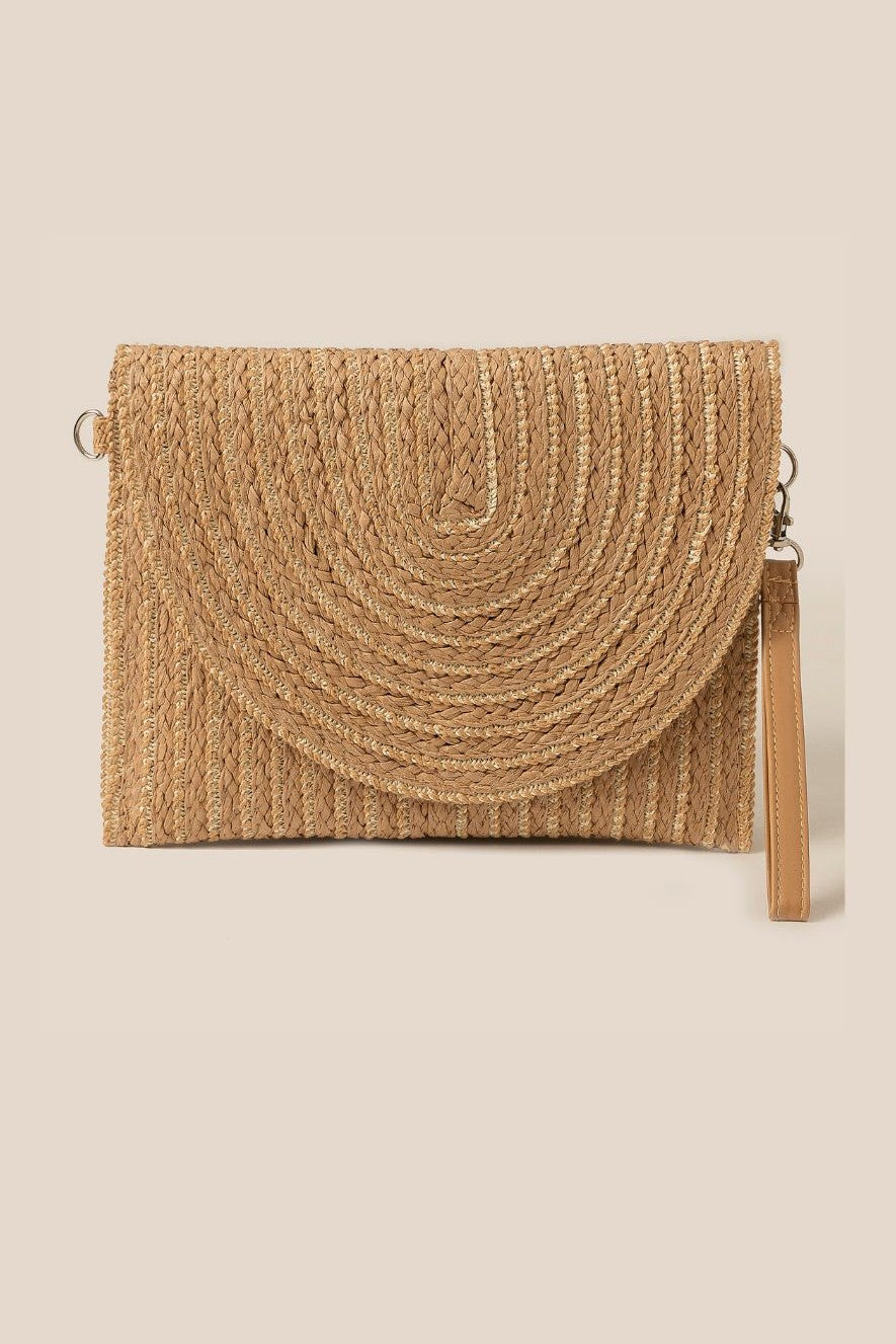 The South Moon Under Straw Woven Clutch features gold accents, a half-moon flap, and a detachable wrist strap, shown against a neutral background.