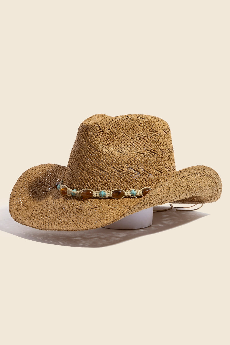 The South Moon Under Beaded Cowboy Hat is a tan straw cowboy hat with a curved brim, featuring a decorative band of small turquoise and tan beads and shells around the crown, shown on a neutral background.