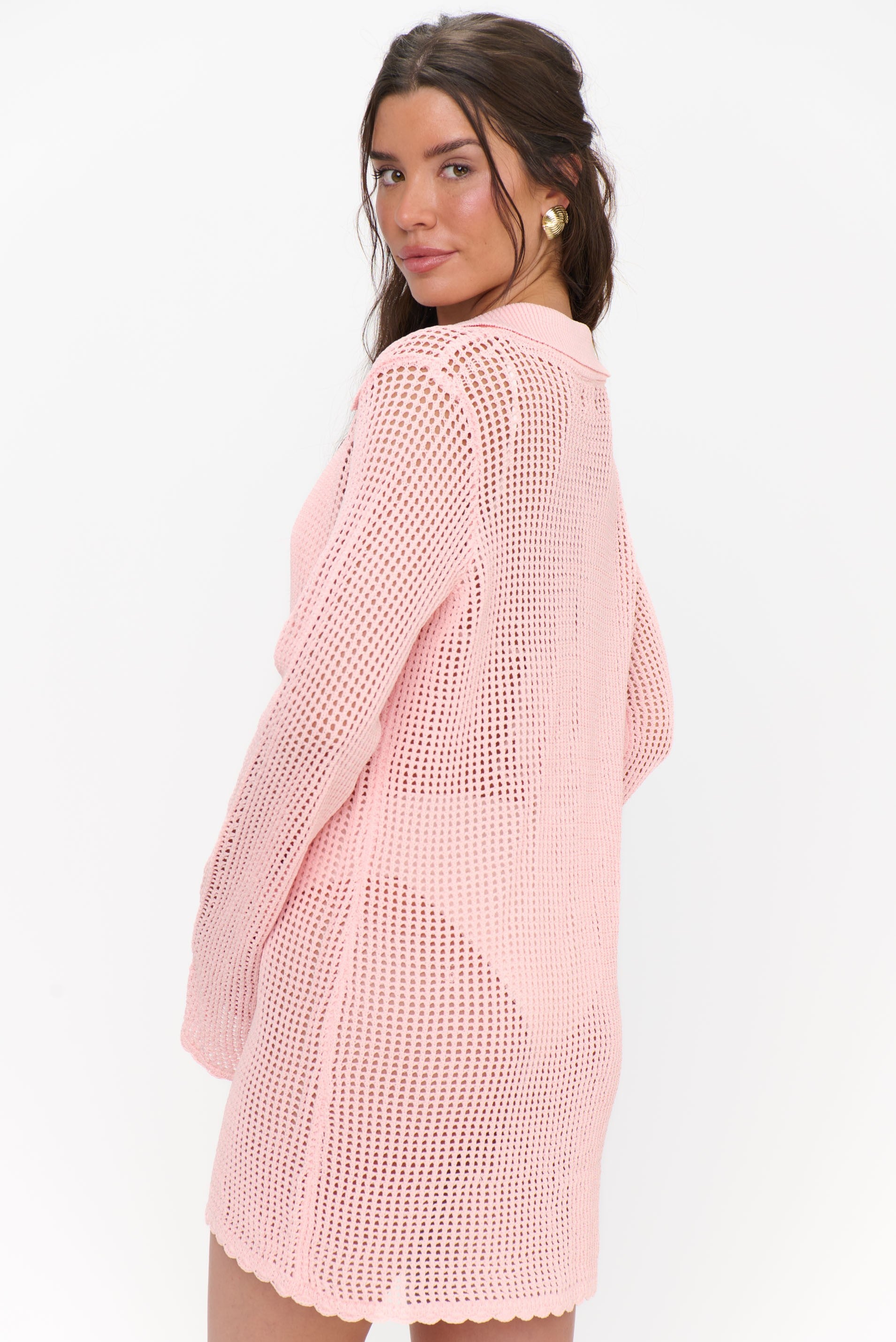 A woman with long brown hair models the Show Me Your Mumu Button Up Coverup in peachy pink over a matching bikini, standing at an angle and looking over her shoulder against a plain white background.