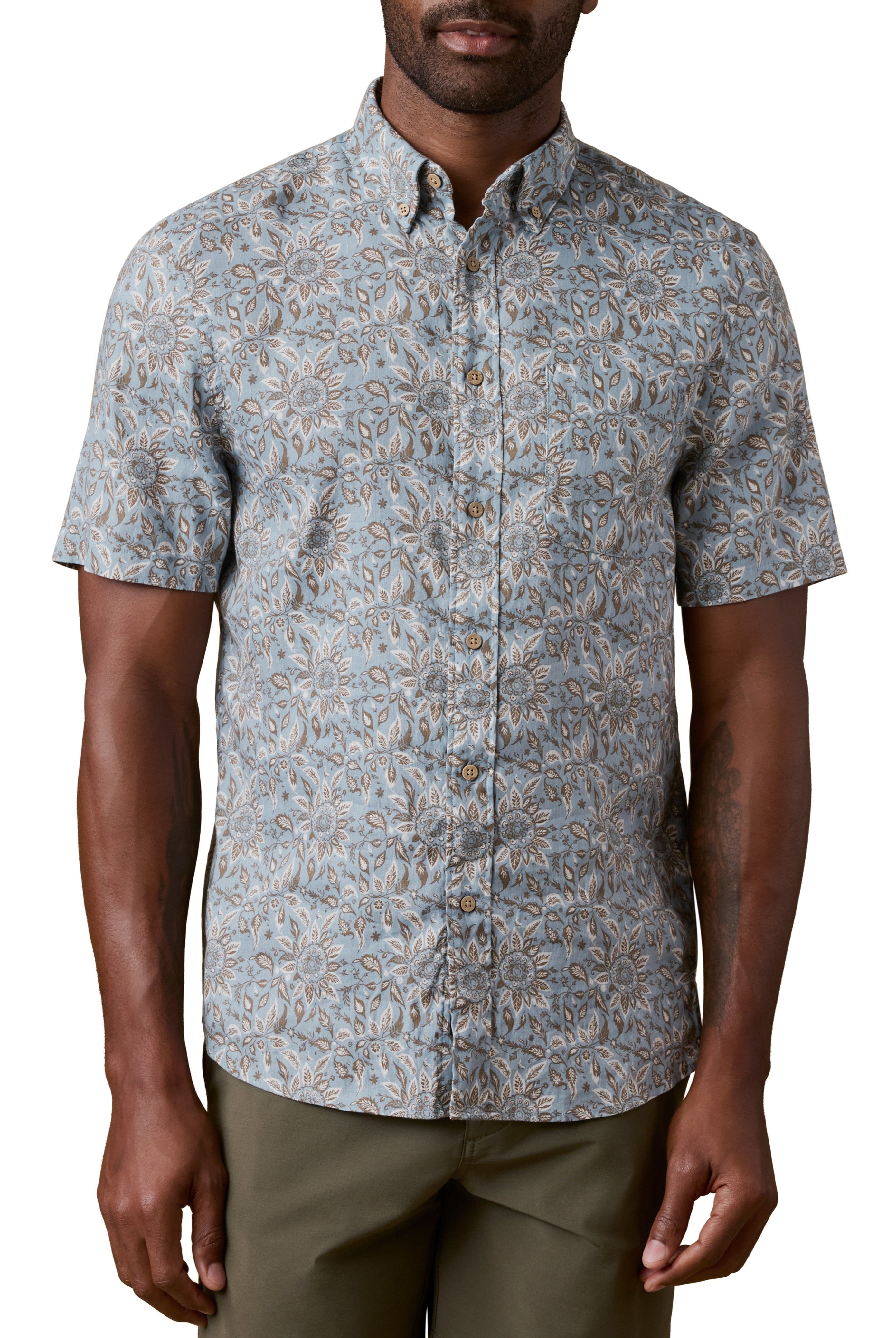 A man wearing the Faherty Short Sleeve Breeze Shirt in Multi, featuring a relaxed fit and vacation style, paired with olive green pants.