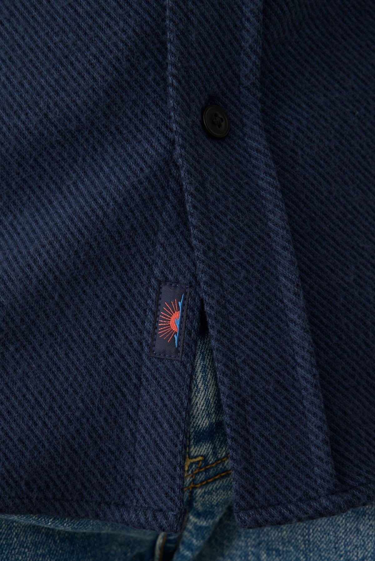 Navy blue sweater shirt with button front, textured fabric, and embroidered logo detail on placket.