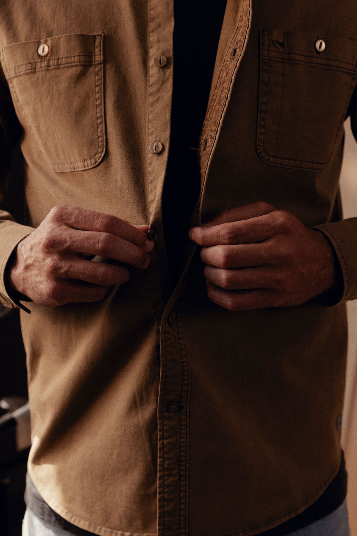 Tan long-sleeve button-up shirt with chest pockets and button front closure, worn open.