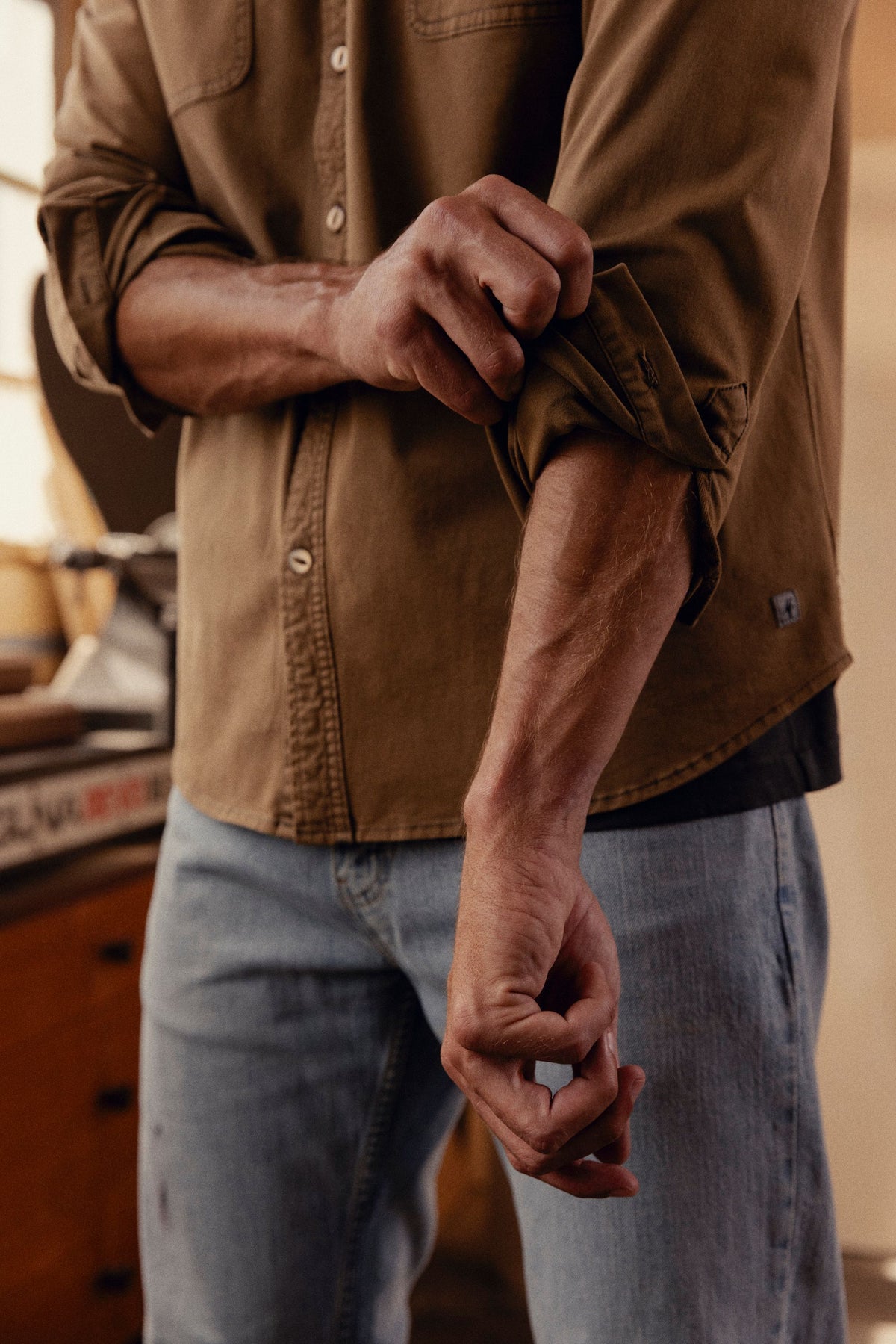 Brown long-sleeve button-up shirt with chest pocket worn with blue jeans.