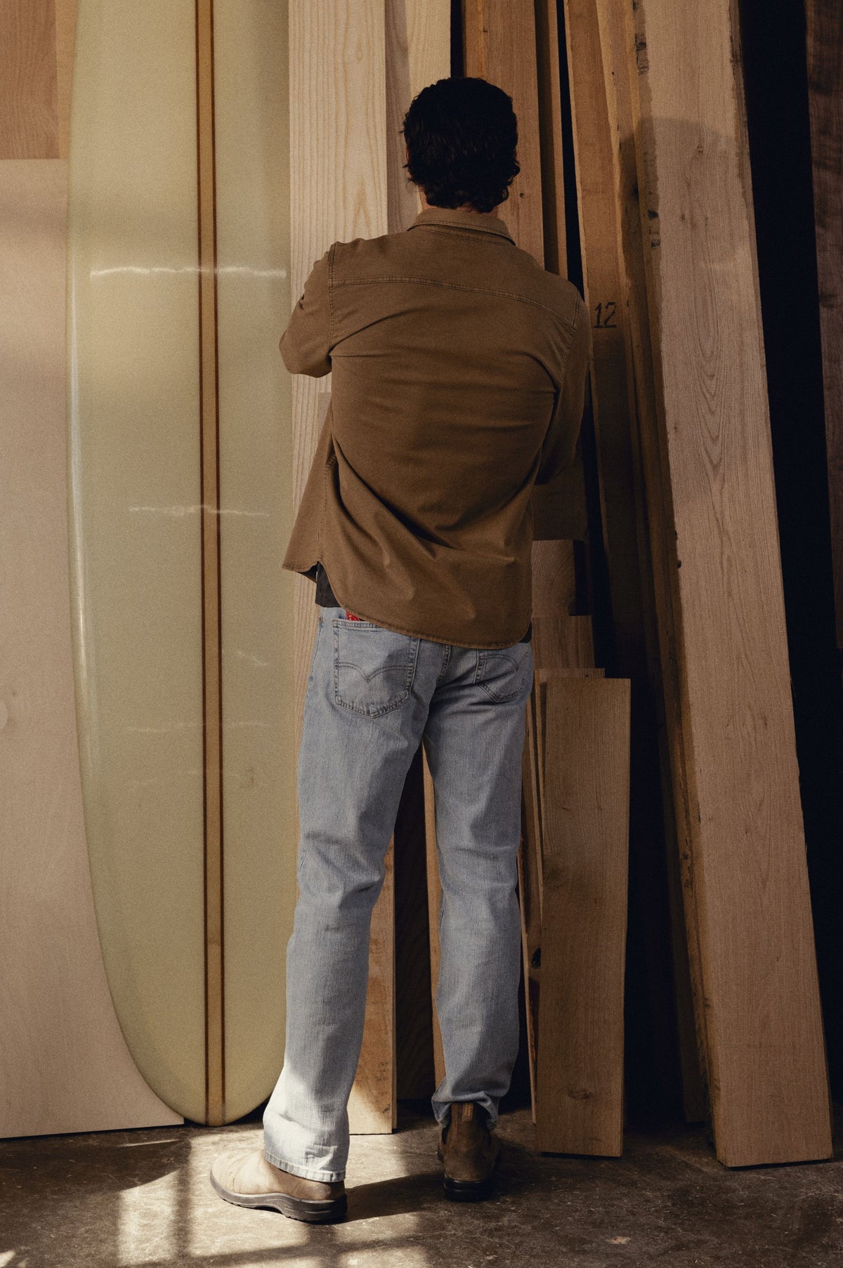 Brown long-sleeve button-up shirt worn with light-wash jeans, shown from back view.