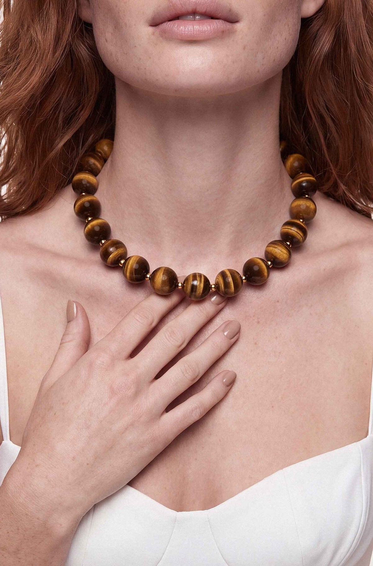 Chunky tiger's eye beaded necklace with striped golden-brown stones worn on model's neck.