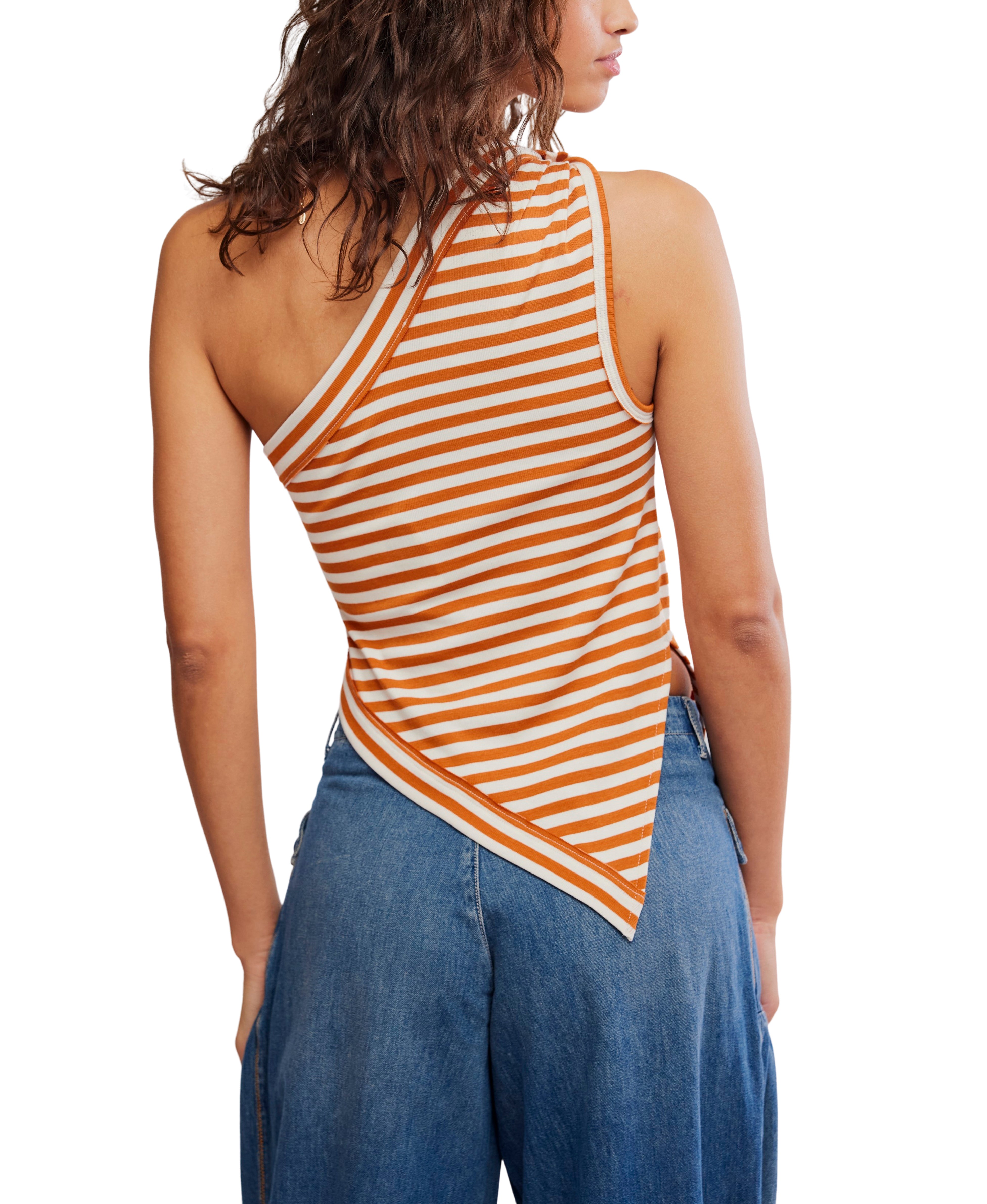 A woman is seen from the back against a white background, wearing the Free People Knot My Vibe in Butter Pecan—an orange and white striped, one-shoulder top with an asymmetrical hem—paired with blue jeans.