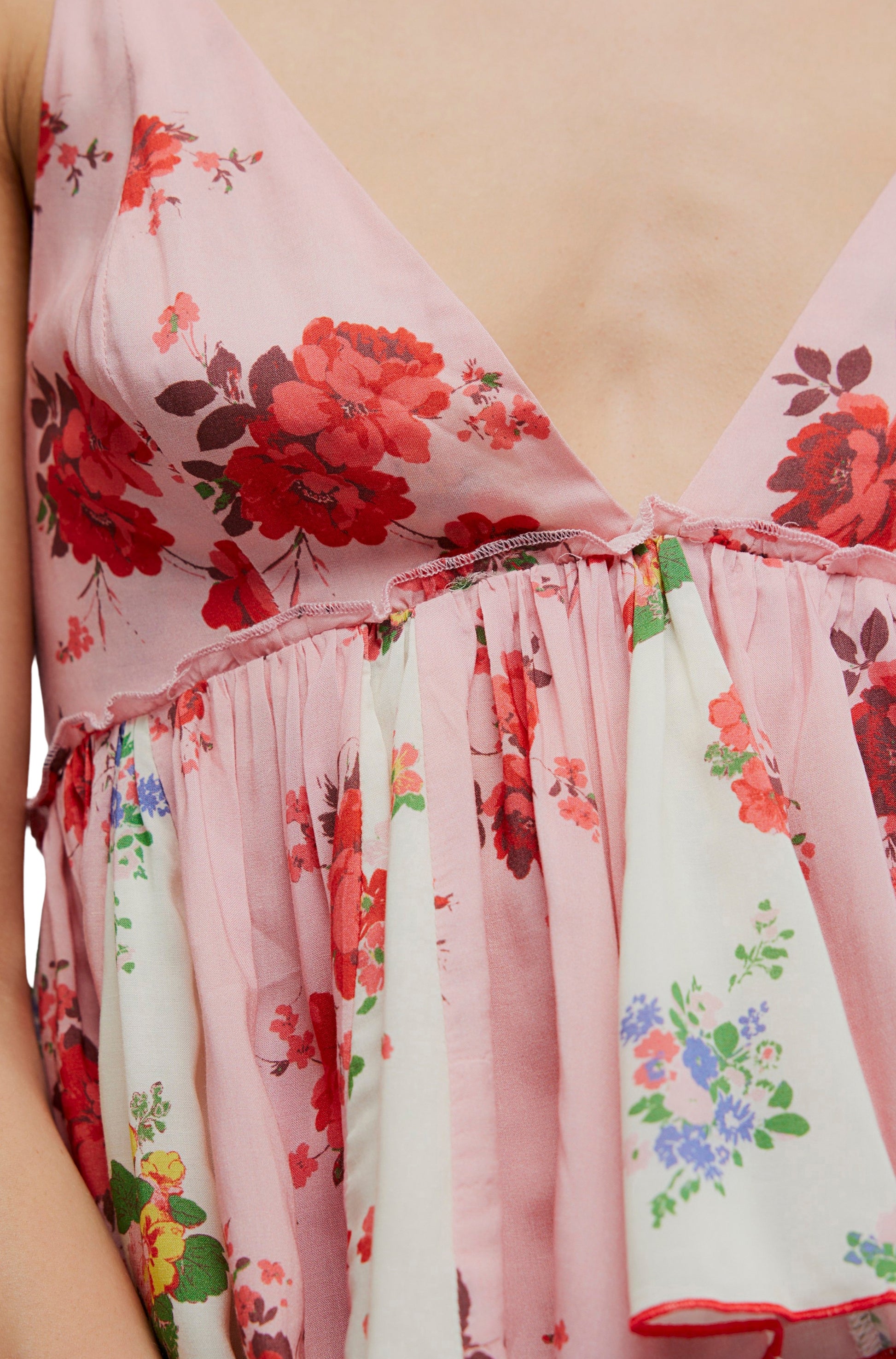 Close-up of the Free People Tillie Top, a sleeveless style with a deep V-neckline, pink and white panels featuring red and blue floral prints, gathered under the bust, and an elegant ruched back.