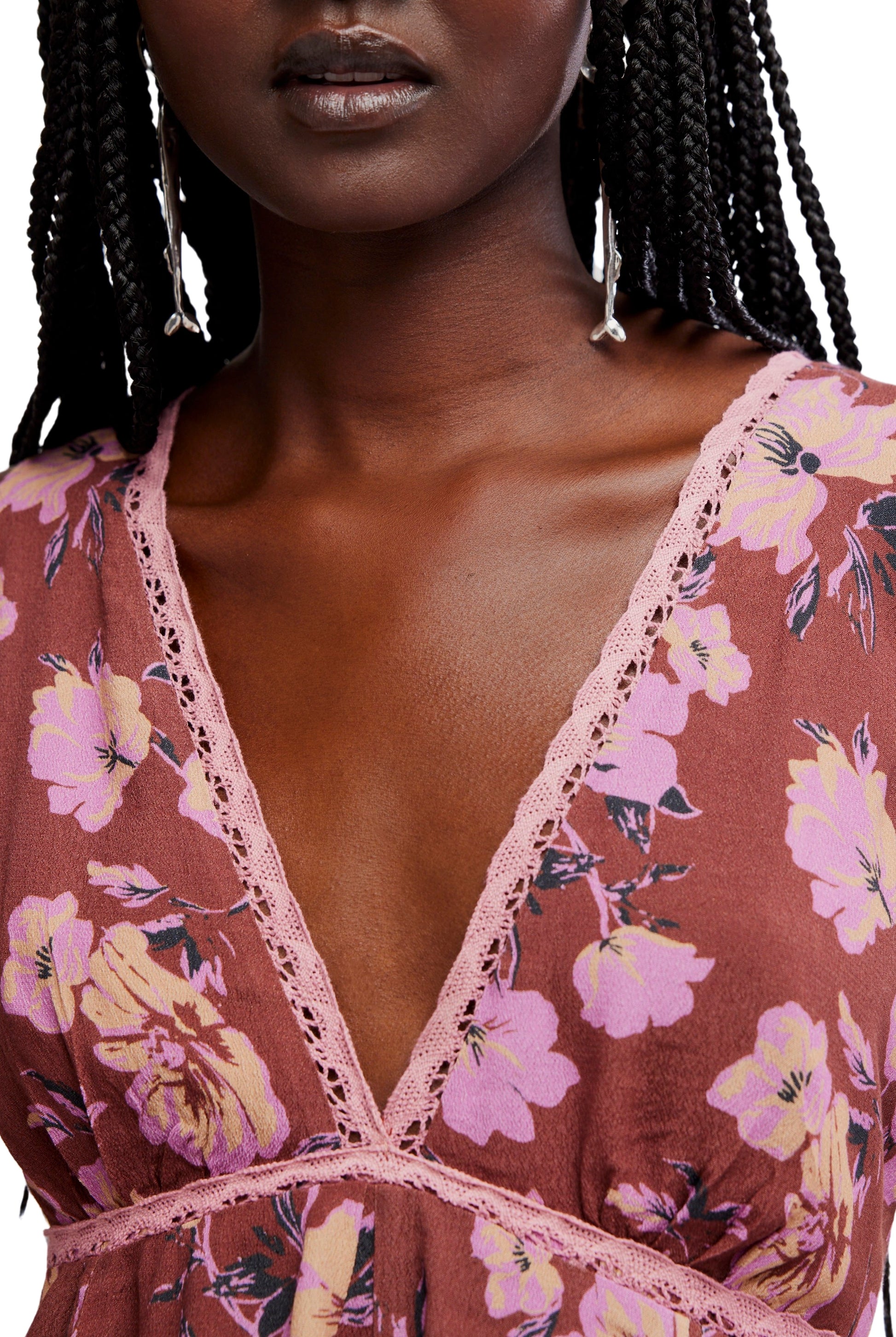 A person with dark braided hair wears the Free People Rome Printed Tank, featuring a mauve floral print and pink lace trim. Only their lower face and upper torso are visible.