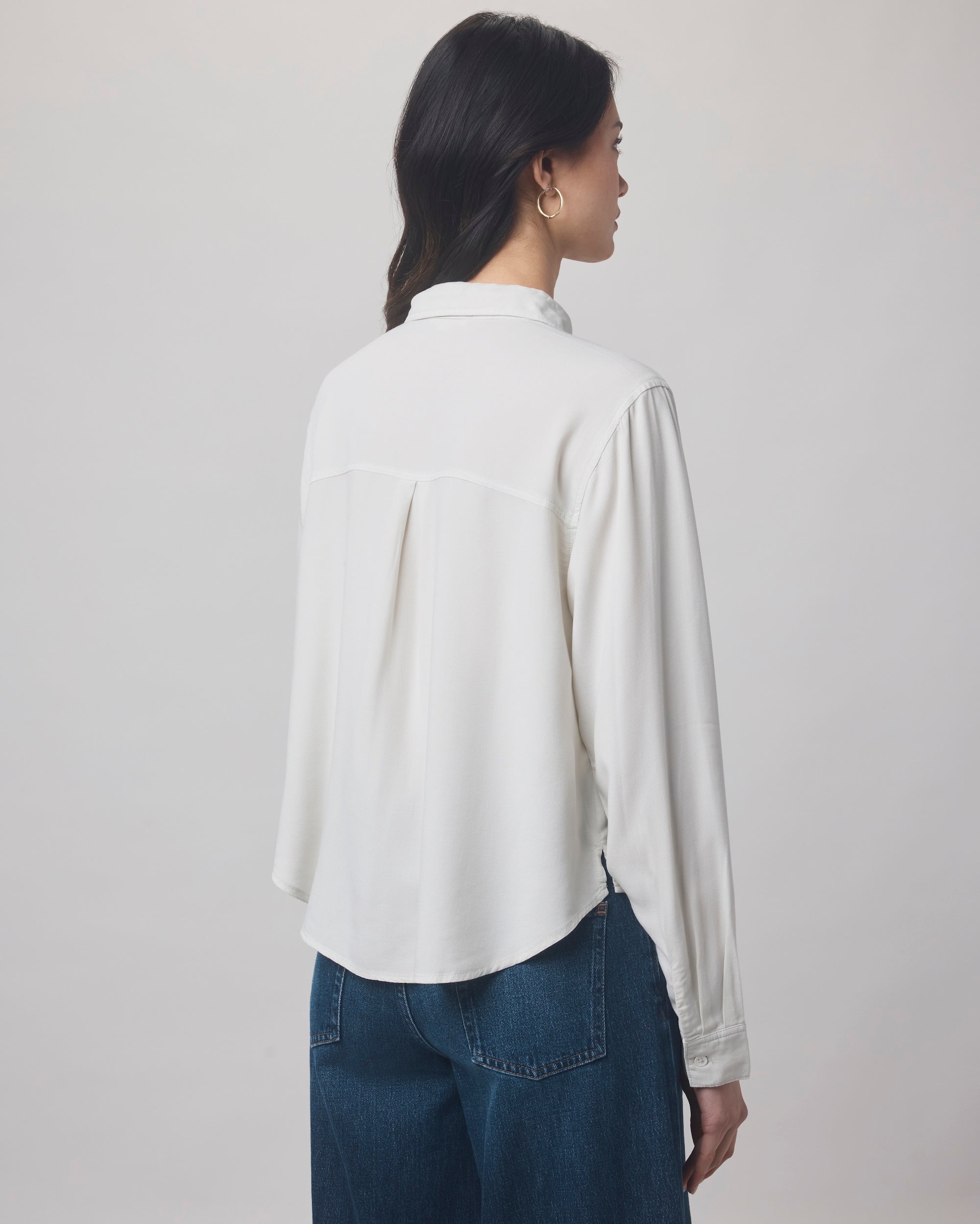 A woman with long dark hair models the Splendid Joanne Blouse, a white collared top, paired with blue jeans and shown from the back against a plain light background.