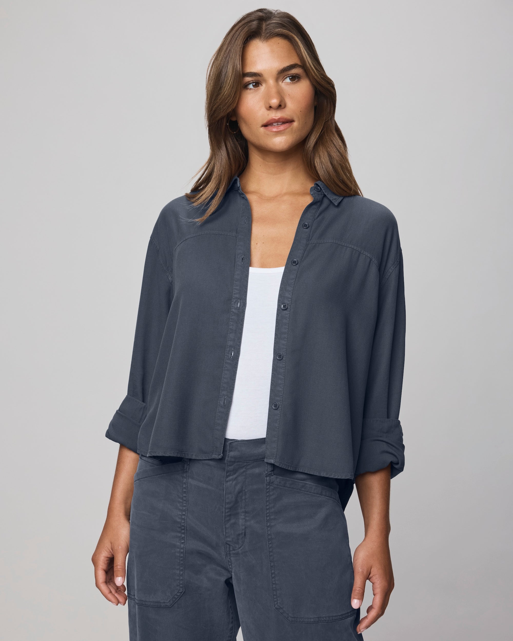 A woman with long brown hair models the Splendid Joanne Blouse in dark blue, paired with matching pants and a white top, standing against a plain grey background.