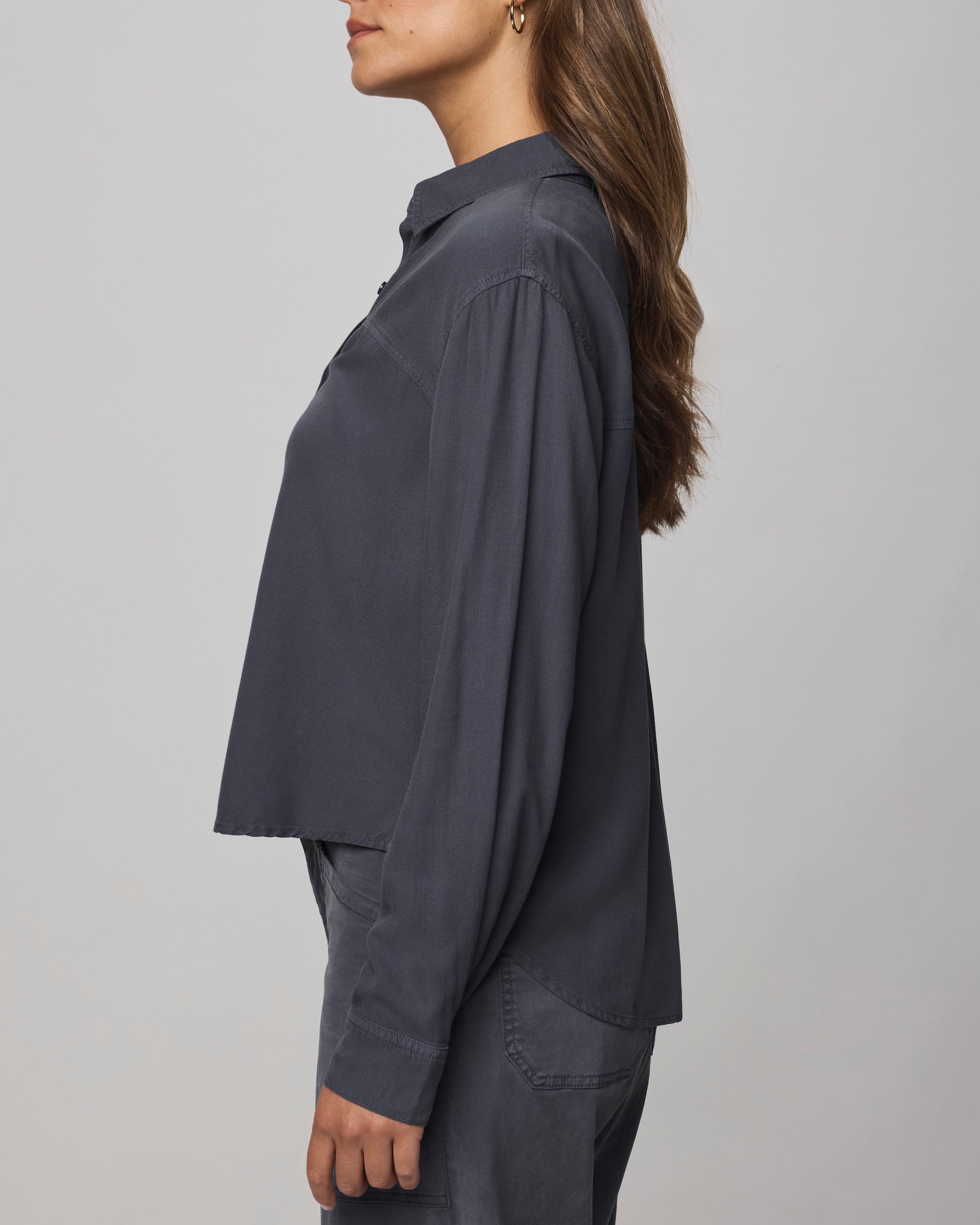 A woman stands in profile against a light gray background, wearing the Splendid Joanne Blouse with matching pants. Her long brown hair is worn down.