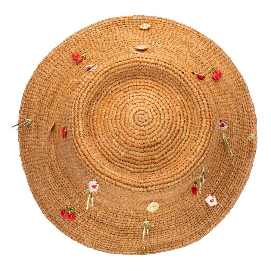 The Charm Bucket Hat by San Diego Hat Co. is a round raffia straw sun hat, topped with cherry charms, gold ribbons, and heart-shaped accents—an adjustable and stylish accessory perfect for sunny days.