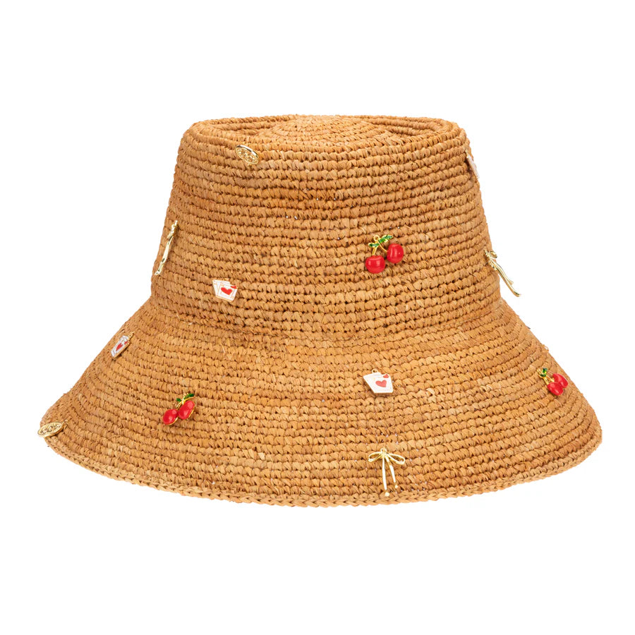 The Charm Bucket Hat by San Diego Hat Co. is a raffia straw hat with small embroidered red cherry and heart motifs, golden bows throughout, and UPF 50+ for stylish sun protection.