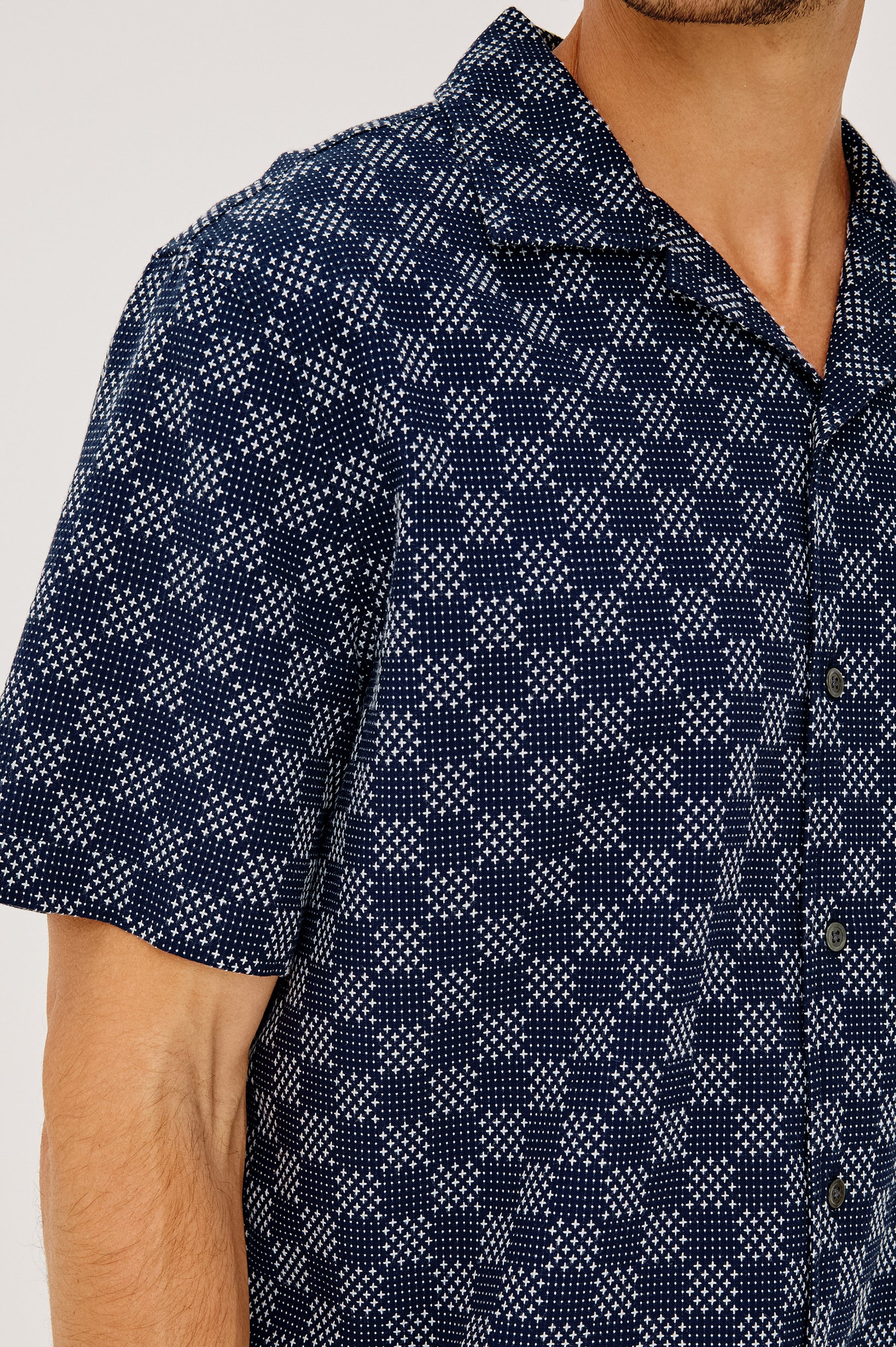 A man wearing the Rails Kin shirt, featuring a relaxed fit and camp collar in navy blue with a white geometric checkered pattern. The image captures his upper body from shoulders to mid-torso.