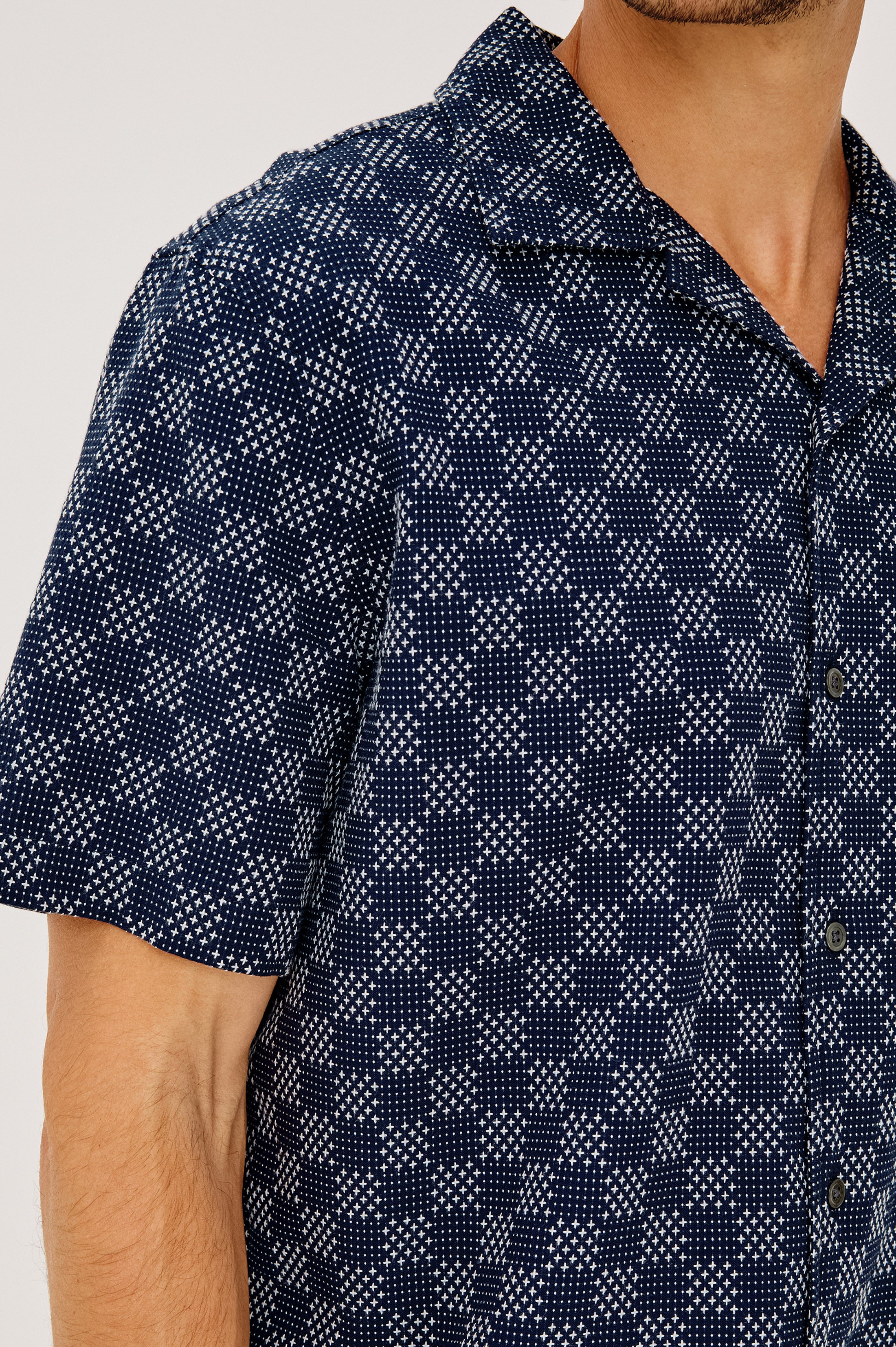 A man wearing the Rails Kin shirt, featuring a relaxed fit and camp collar in navy blue with a white geometric checkered pattern. The image captures his upper body from shoulders to mid-torso.