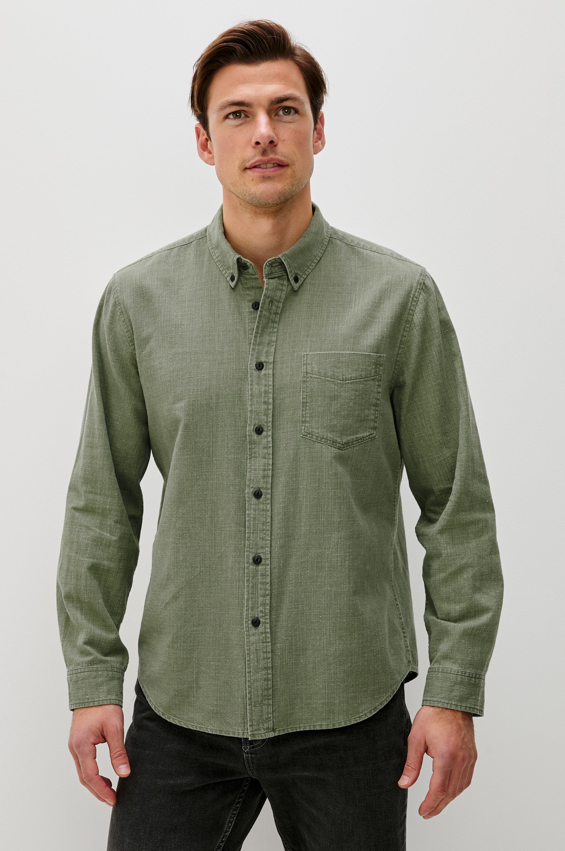 A man with short brown hair wears the Rails Tristan Button Down Shirt in light green, made from 100% cotton, paired with black pants. He stands against a plain white background facing forward with a neutral expression.