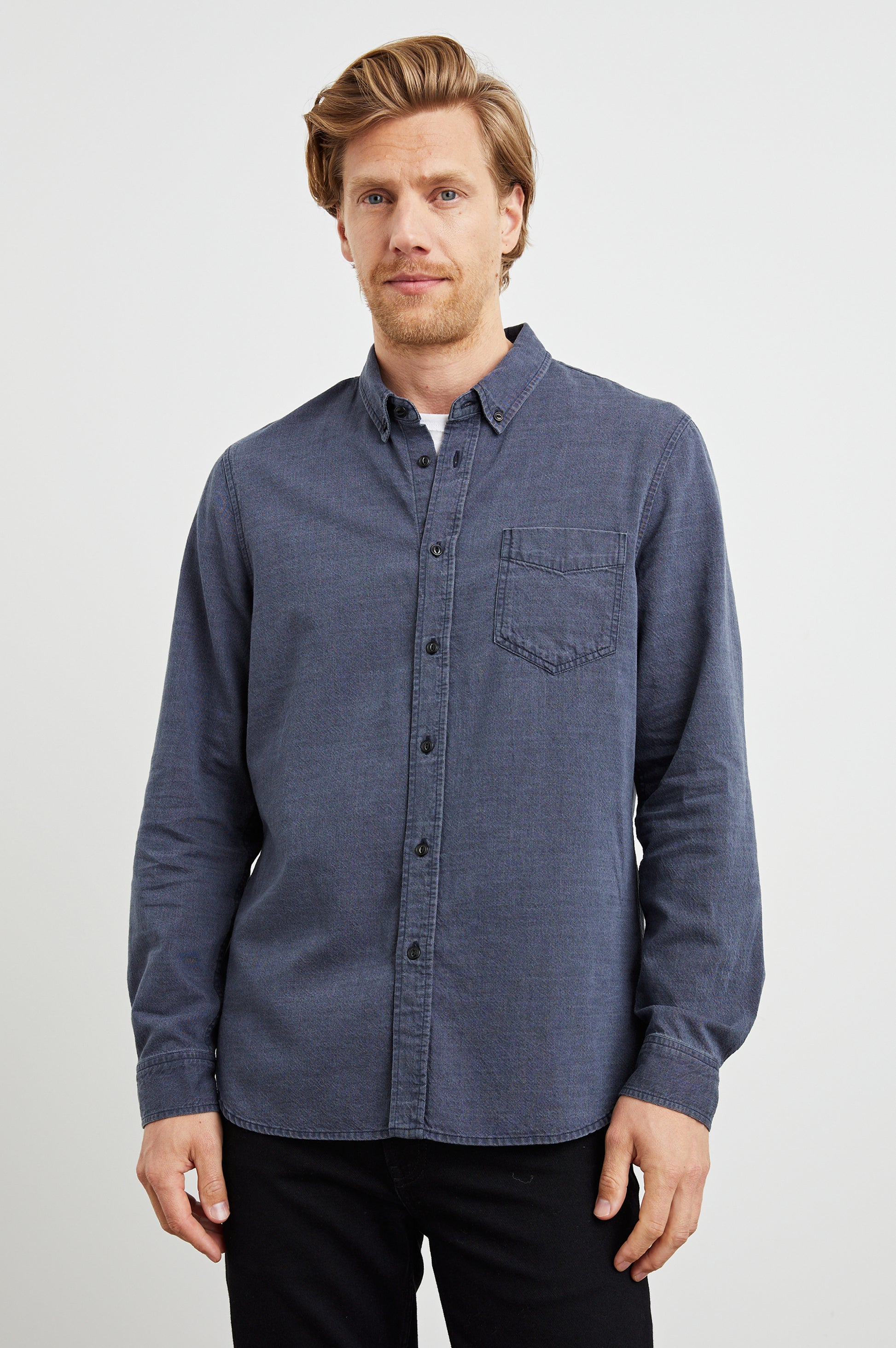 A man with light brown hair and a short beard is wearing the Rails Tristan Button Down Shirt in dark blue and black pants, standing against a plain white background.