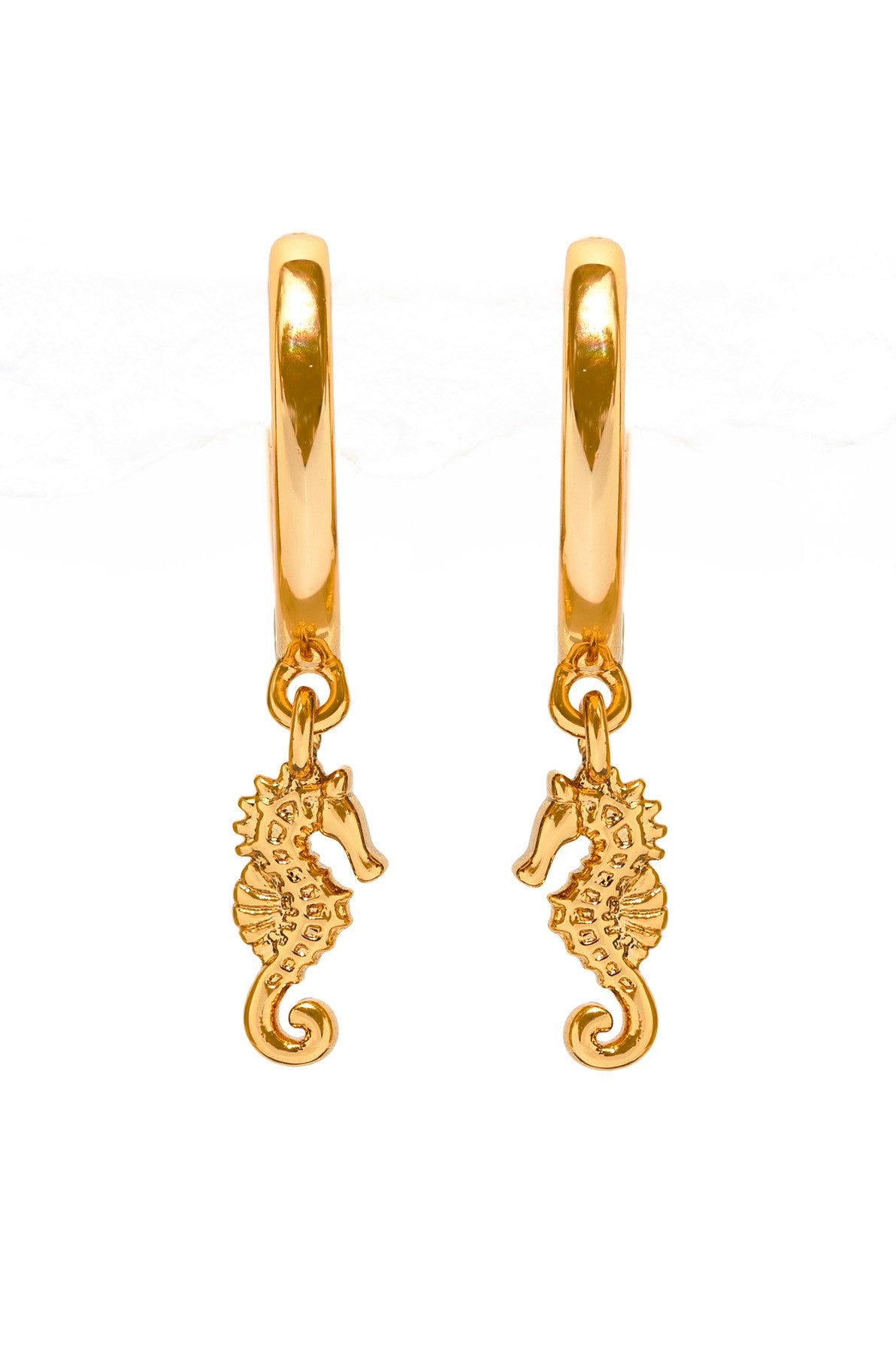 The Girls Crew Simple Seahorse Hoops are gold huggie earrings featuring detailed seahorse charms on each hoop, displayed against a white background.