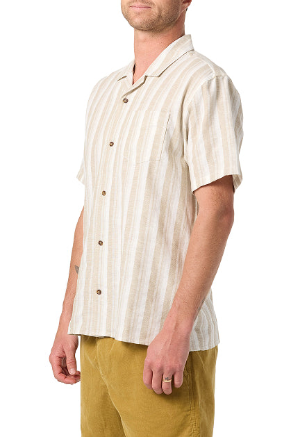 A man wears the O'Neill Dobby Standard Short Sleeve Woven Shirt, featuring light beige and white stripes, a camp collar, and chest pocket, paired with mustard yellow pants against a white background.