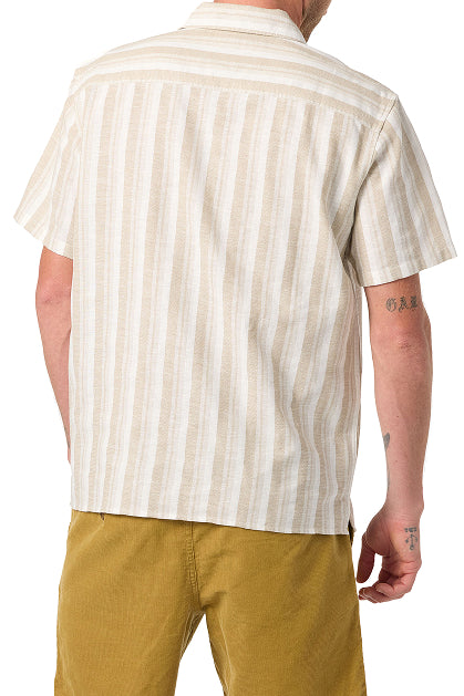 A person is seen from the back wearing O'Neill's Dobby Standard Short Sleeve Woven Shirt in beige and white stripes, paired with mustard yellow shorts. Visible tattoos are on their right arm.