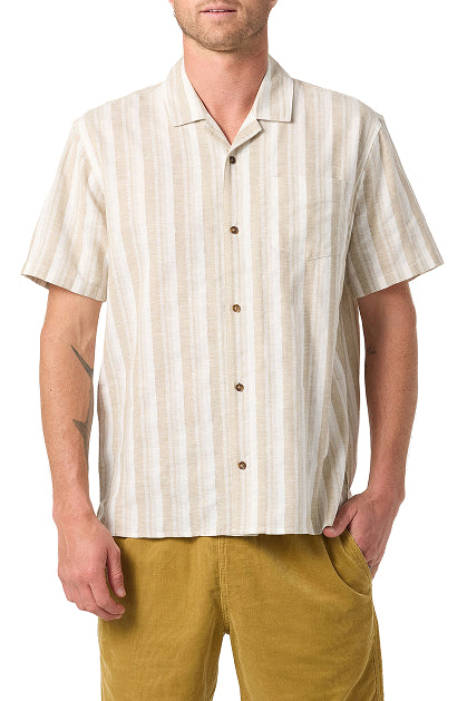 A man wears an O'Neill Dobby Standard Short Sleeve Woven Shirt in beige and white stripes with mustard yellow pants, standing with one hand in his pocket.