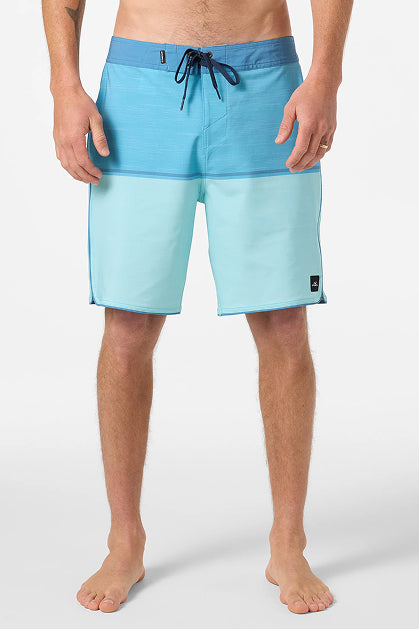 A person stands barefoot in O'Neill Hyperfreak Mysto Block 19 In Boardshorts, featuring light blue fabric with a dark blue waistband and drawstring, made from recycled polyester, shown from shoulders to feet against a plain white background.