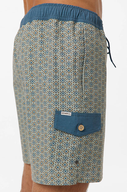 A person wears O'Neill's Hermosa Retro 17 In Swim Trunk: mid-length, water-resistant swim shorts with geometric patterns, a blue waistband, and a blue flap pocket secured by a wooden button—offering style and durability.