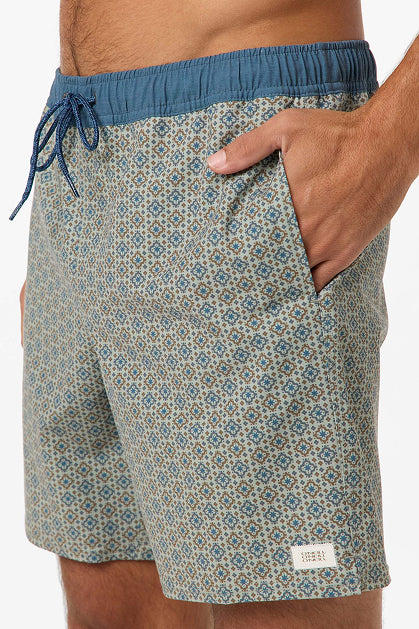 Man wearing O'Neill Hermosa Retro 17 In Swim Trunk—patterned blue and tan recycled polyester shorts with a blue waistband, drawstring, side pocket, and a small white label near the hem.