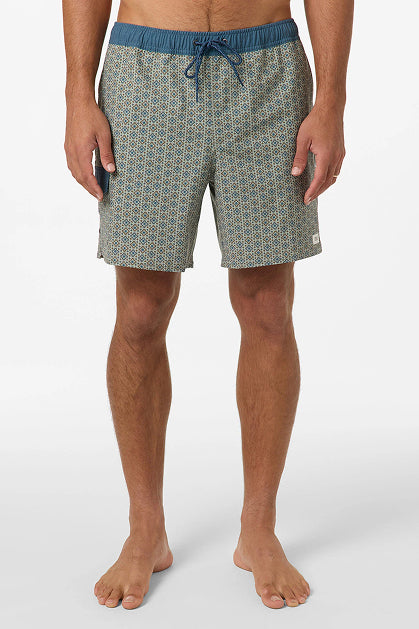 A man wears O'Neill Hermosa Retro 17 In Swim Trunks, patterned and water-resistant with Hyperdry technology, a blue waistband, and drawstring. He stands barefoot, shown from mid-chest down against a plain white background.