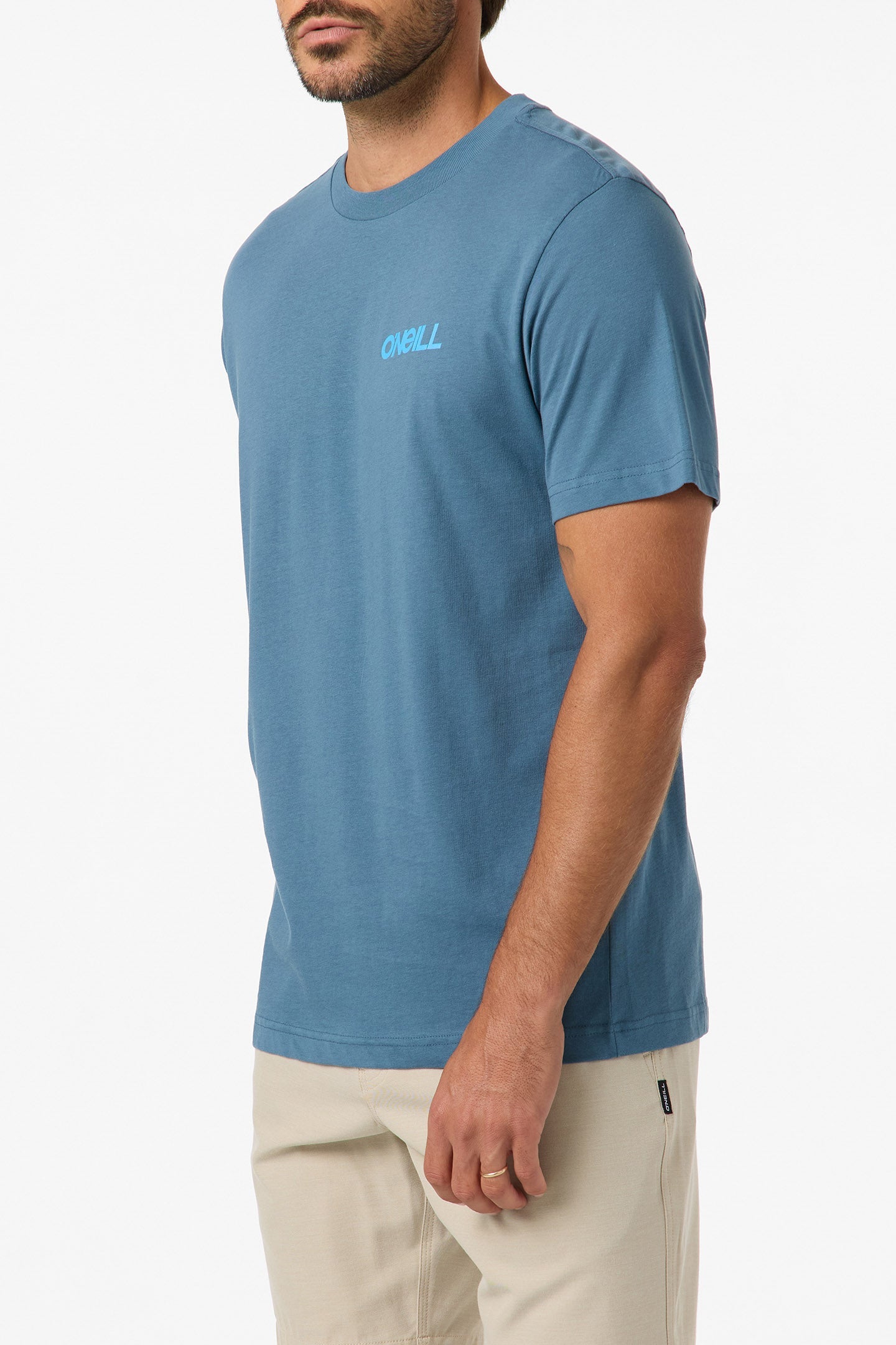 A man wearing the O'Neill Dawn Classic Short Sleeve Tee with a soft hand screen print and beige pants stands against a white background, facing slightly to the side with his arms relaxed by his sides.