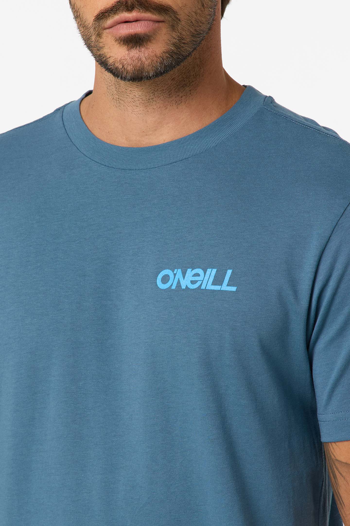A man wears the O'Neill Dawn Classic Short Sleeve Tee, featuring the brand name in light blue on the chest. Made from 100% cotton with a soft screen print, only his lower face and upper torso are visible.