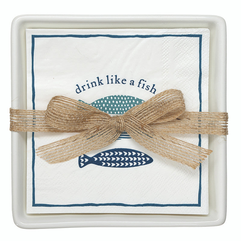 The Drink Like A Fish Napkin Set by Santa Barbara Design Studio features white multi napkins with blue fish art and “drink like a fish” text, tied with a beige ribbon and placed on a square white tray.