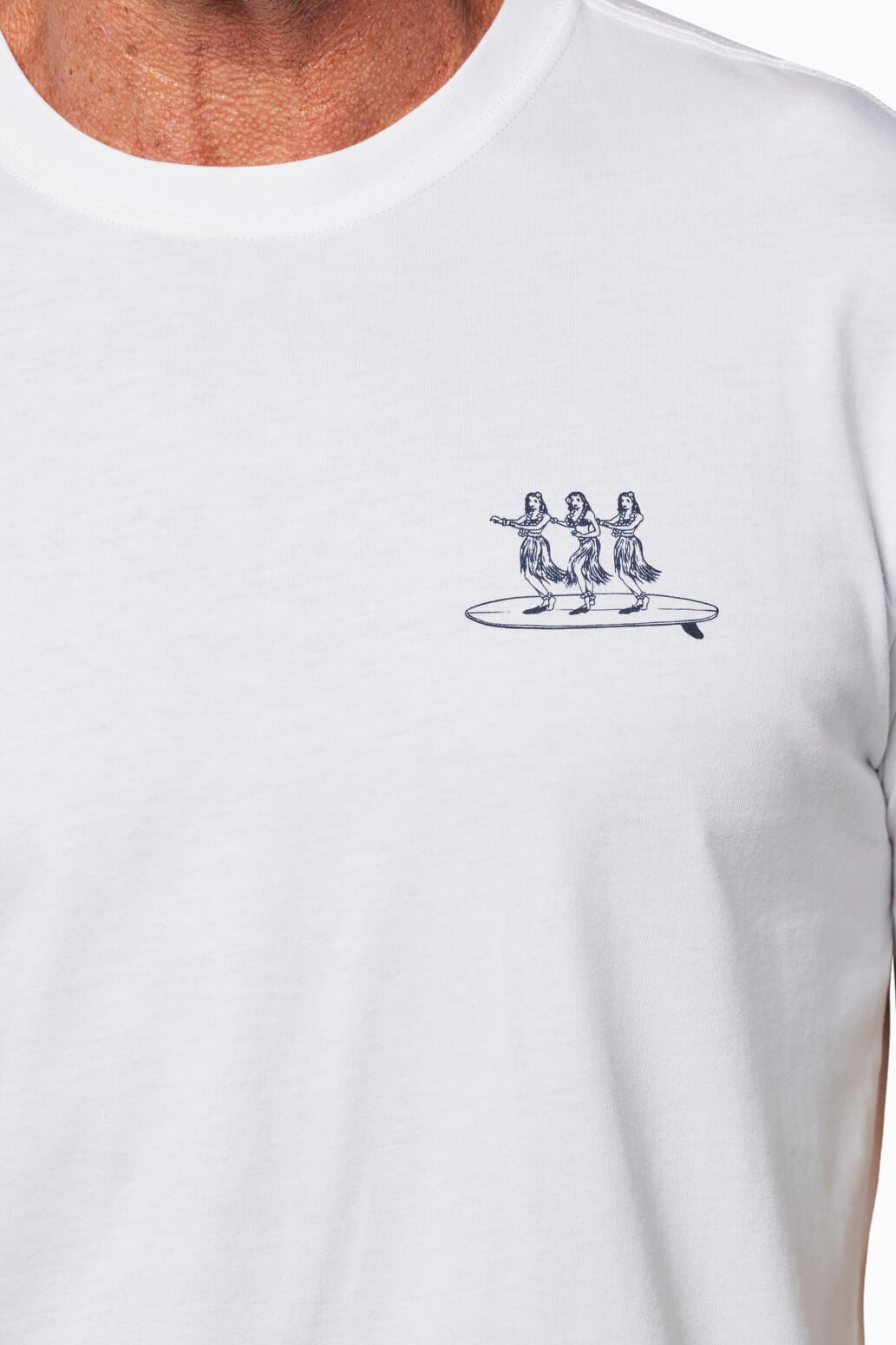 Close-up of the Toes on the Nose Hula Board Short Sleeve Tee— a relaxed fit white T-shirt made from premium Peruvian cotton, featuring a small chest graphic of three hula dancers standing on a surfboard.