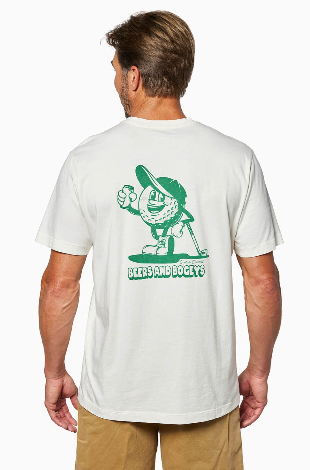 A man, seen from behind, wears the Toes on the Nose Beers And Bogeys white relaxed fit T-shirt in premium Peruvian Cotton, featuring a green cartoon golf ball, Captain Cocktail, with BEERS AND BOGEYS text on the back.