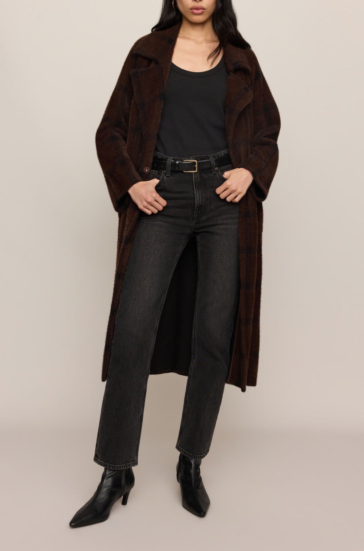 Woman wearing a dark brown cocoon coat over a black top and dark jeans with a black belt.
