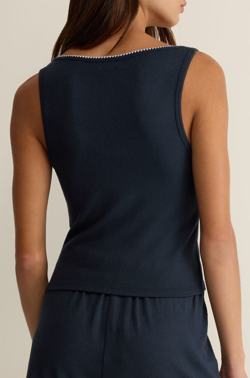 A woman with brown hair stands against a neutral background, wearing the Z Supply Stately V-neck Tank in navy blue and matching shorts, highlighting this versatile sleeveless top from the back.