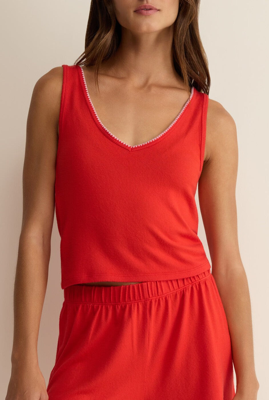 A woman models the Z Supply Stately V-neck Tank in red with matching elastic-waist bottoms, creating an effortless look against a neutral background. Her face is partially out of frame.