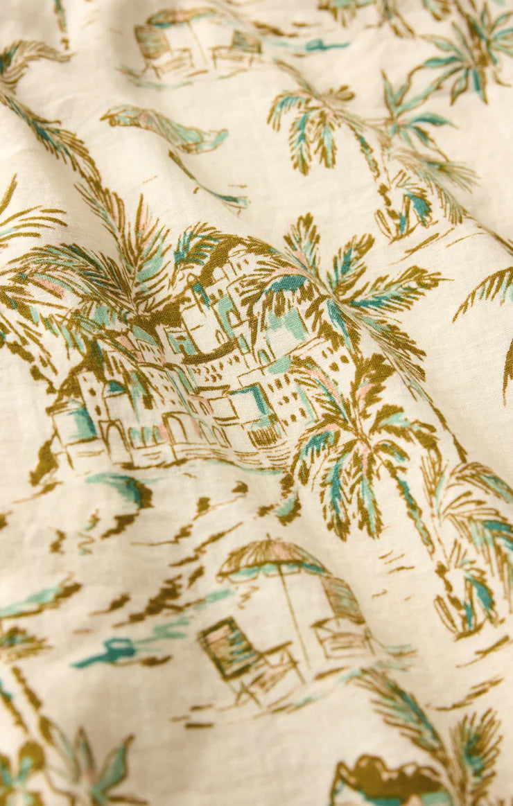 The Overlook Tiki Tide Linen Pant by Z Supply features cream-colored washed linen with a vintage palm tree, beach chair, and building print in green and brown—a textured fabric perfect for relaxed, high-rise wide leg pants.