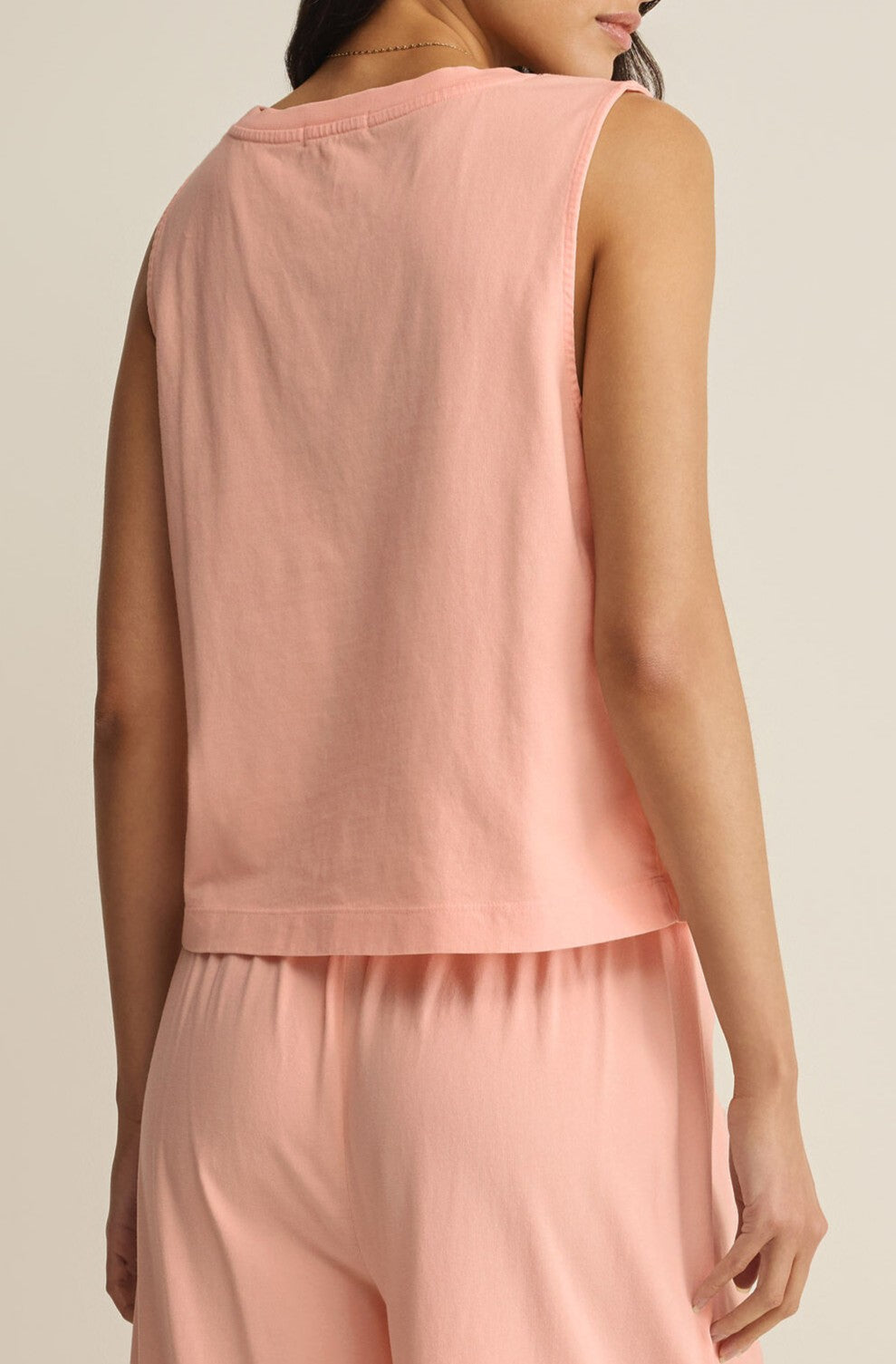 A woman is seen from the back wearing the Z Supply Sloane V-neck Top in light pink, a sleeveless, relaxed fit cotton jersey tank, paired with matching pants. The look is comfortable and casual against a neutral background.