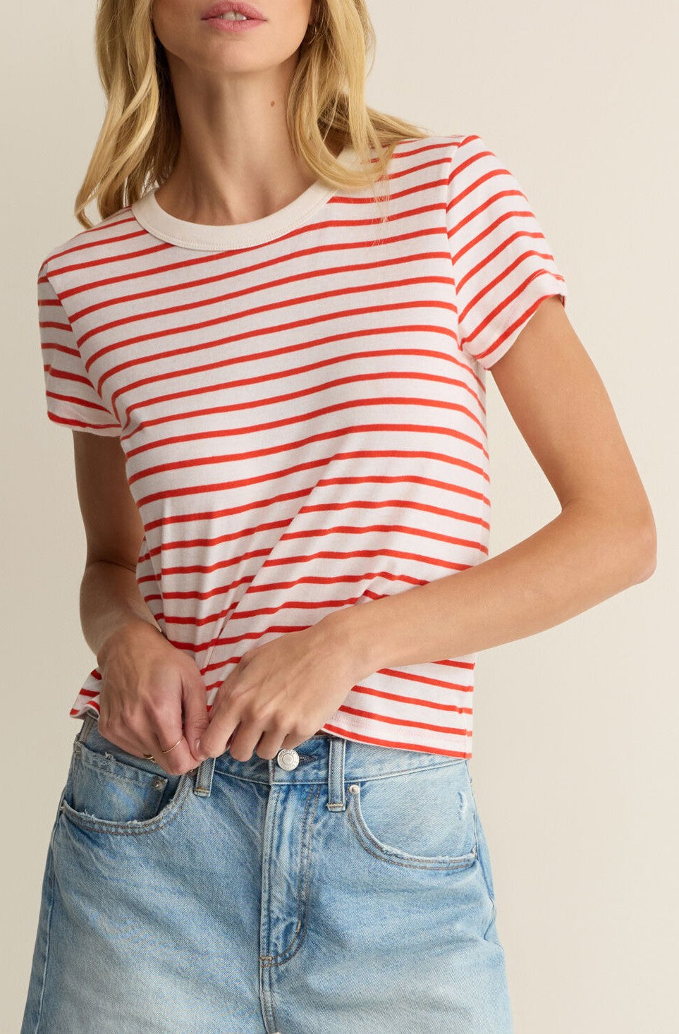 Someone is wearing the Z Supply Junie Striped Tee, a white crew neck with red horizontal stripes, made from premium brushed slub jersey, tucked into light blue high-waisted jeans against a plain light-colored background.